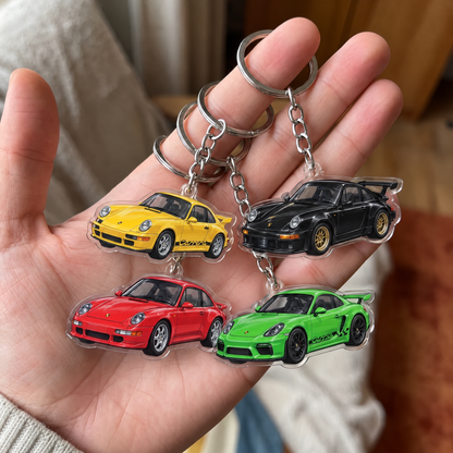 Four Porsche acrylic keychains held in a hand